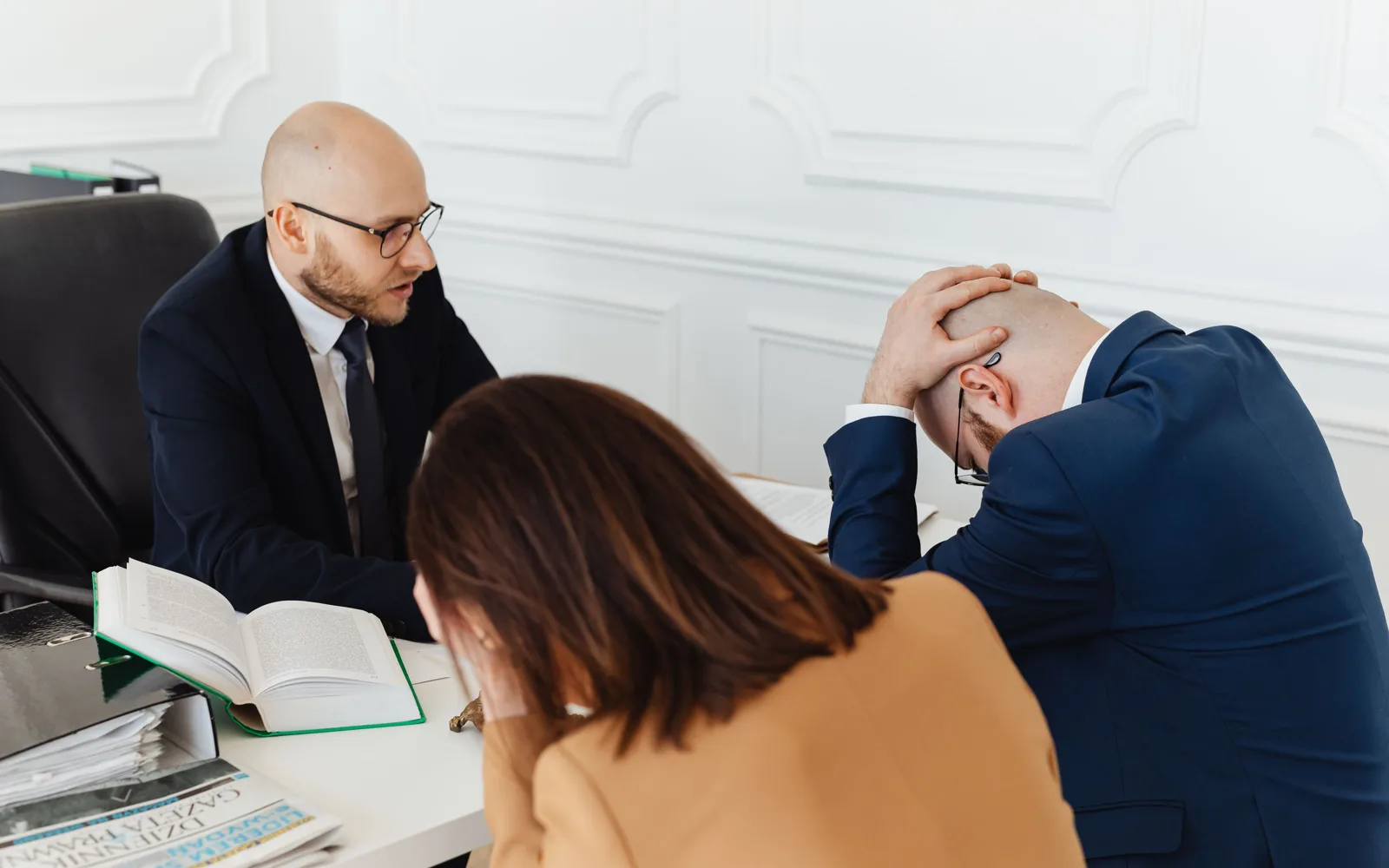 Deux professionnels en échange tendu autour de documents ouverts sur la table
